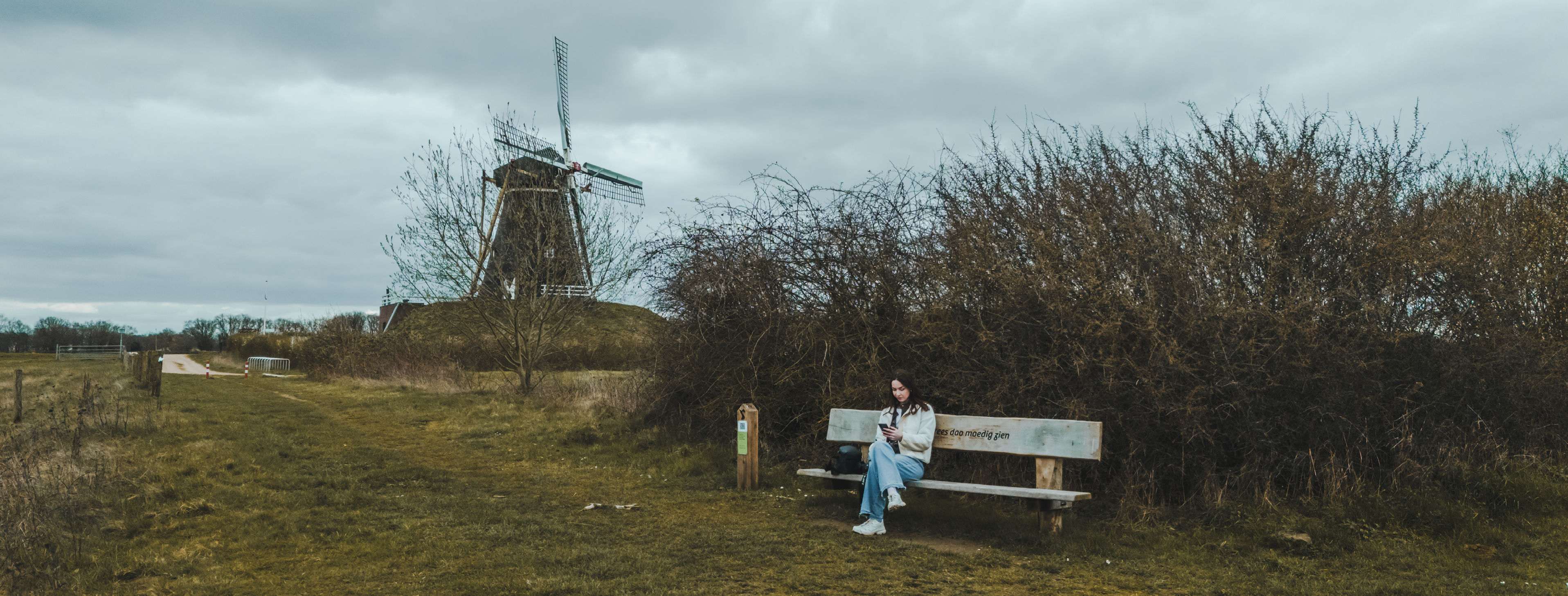 Molen in landschap met vrouw op een bankje