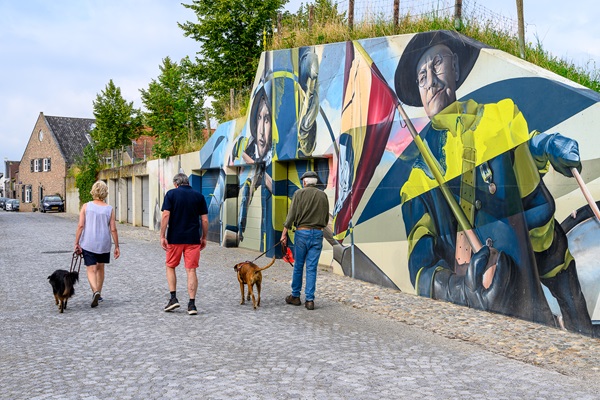 Spaziergänger mit Hunden gehen an Stevensweert-Straßenkunst vorbei, die die spanischen Eroberer darstellt