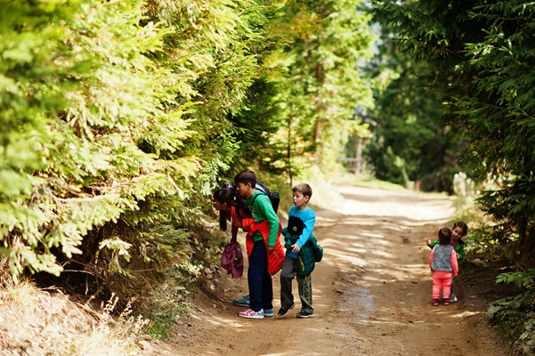 Kinderen en hun moeder kijken naar iets in het bos terwijl de twee kleinste naar iets anders kijken