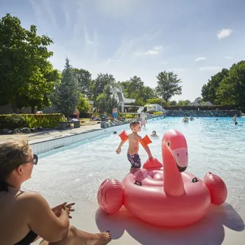Kind speelt met een roze flamingo in het buitenbad van De Leistert op een zonnige dag